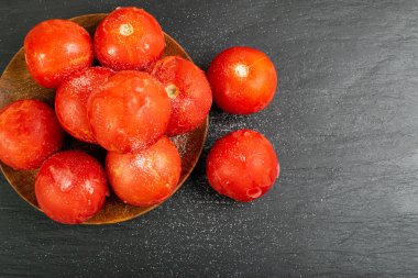Frozen Tomatoes on Black Stone Background, Whole Iced Tomato Pile, Frozen Red Vegetables Pile