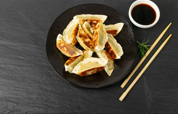 stock image Gyoza Chinese Dumplings on Black Plate, Fried Vegetable Jiaozi, Chicken Momo Pile, Asian Gyoza Group, Stone Background, Top View, Copy Space