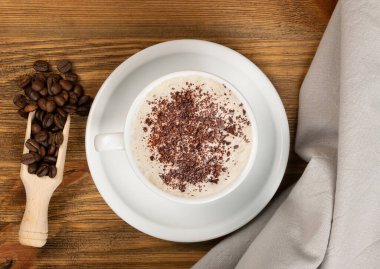 Kahverengi ahşap masa arkası manzaralı kahve çekirdekli sıcak espresso bardağı. Beyaz kahve ya da siyah içecek üst görünümü olan kupa.