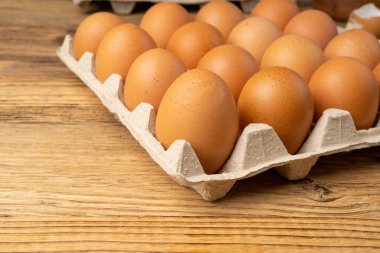 Tahta taşra arka planında yumurta tepsisi, 20 kahverengi yumurta paketi, kağıt kabın içinde 20 taze organik yumurta.