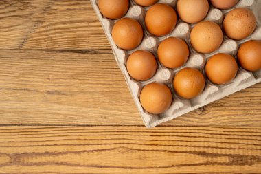 Tahta taşra arka planında yumurta tepsisi, 20 kahverengi yumurta paketi, kağıt kabın içinde 20 taze organik yumurta.