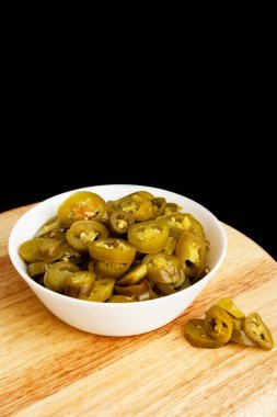 Turşulu Jalapeno Pile, Baharatlı Yeşil Jalapenos, Sıcak Meksika Biber Dilimleri Beyaz Bowl, Tahta Masa 'da Turşulu Yeşil Jalapeno, Kara Arkaplan