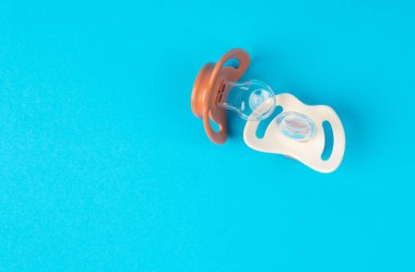 Emzik izole edilmiş, ortodontik bebek mankeni, lastik pastel çocuk yatıştırıcısı, mavi zeminde yeni sağlıklı silikon emzik.