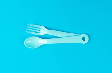 Bebek kaşığı ve çatal izole edilmiş, Plastik Çocuk Çay kaşığı, Renkli Çocuklar Utensil, Küçük Renkli Bebek Masası takımı, Mavi Arkaplanda Yeni Bebek Kaşıkları