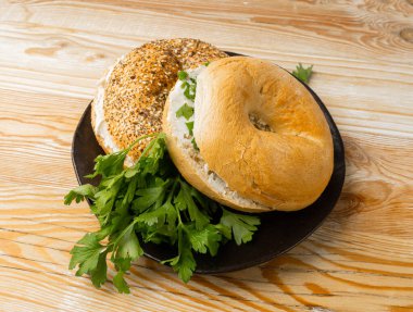 Yumuşak peynirli ve yeşillikli yarım simit, izole edilmiş yuvarlak ekmek ekmeği, tahıllı buğday fırını ve kahvaltılık tohumlar, beyaz arka planda düz yuvarlak bagel ekmeği.
