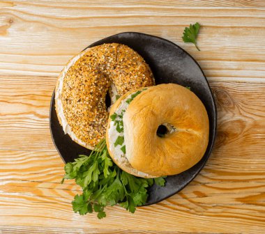Yumuşak peynirli ve yeşillikli yarım simit, yuvarlak ekmekli çörek, tahıllı ve tohumlu buğday fırını ve kahvaltılık tohumlu ekmek, tahta masa üzerinde düz halka simit ekmeği Top View