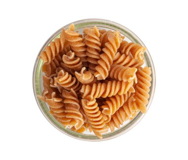 Çiğ kahverengi makarna, kabın içindeki kepekli fusilli istifi, kuru tam tahıllı erişte, çiğ hamurlu makarna, sağlıklı İtalya yemeği, organik yemek, beyaz arka planda kepekli sarımsaklı makarna.