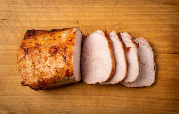 Baked Pork Cut on Wooden Table. Roasted Sliced Loin, Tenderloin Ham Piece, Baked Meat Fillet on Wood Rustic Background