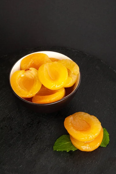 Canned Peaches in Bowl, Apricot Halves in Syrup, Yellow Fruit Dessert, Tinned Nectarine Compote, Orange Peeled Peache Slices on Black Background