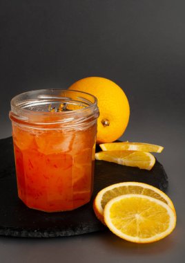 Kavanozda portakal reçeli, kayısı reçeli, meyveli reçel, meyveli jöle karışımı, kaşıkta sarı kırmızı şurup, mango sosu, siyah arka planda turuncu reçel.