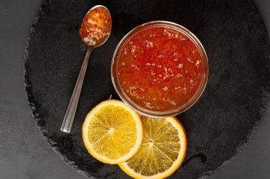 Kavanozda portakal reçeli, kayısı reçeli, meyveli reçel, meyveli jöle karışımı, kaşıkta sarı kırmızı şurup, mango sosu, siyah arka planda turuncu reçel.