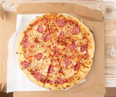 İtalyan pizzası karton teslimat kutusunda, jambonlu pizza yeşil biberli, acı biberli ve Mozzarella peynirli, geleneksel İtalyan yassı ekmeği