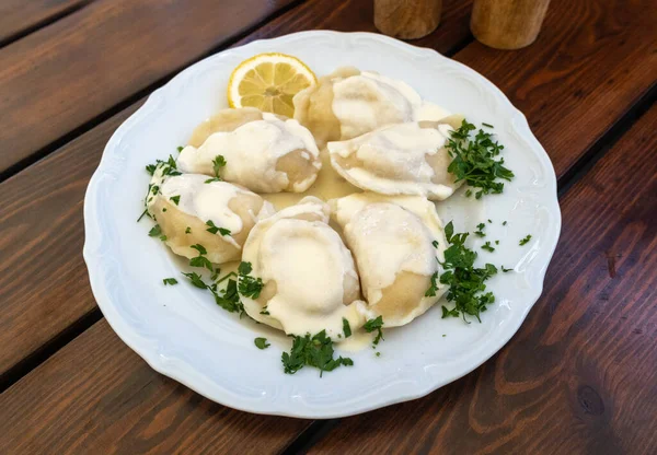 Geleneksel Polonya Pierogi, Pişmiş Hamur köfteleri, Ravioli, Ukrayna Varenyky ve Yeşiller ve Beyaz Restoran Tabağında Ekşi Krema