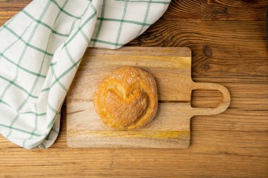 Buğday ekmeğine kalp, tahta masaya kalp şeklinde çörek, ahşap arka planda küçük yuvarlak ekmek.