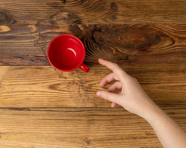 Hand Grabs Cup, Hands Reaching Empty Red Cup, Coffee Mug, Teacup, Hot Beverage Mockup, Cup in Arms on Wood Background with Copy Space for Text Top View