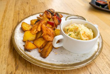 Kümes hayvanları şiş kebap, barbekü şiş kebap, et ve sebzeli ızgara, meyve, biber, soğan ve ananas karışımı lahana salatası ve barbekü sosuyla servis edilen restoran tabağı.