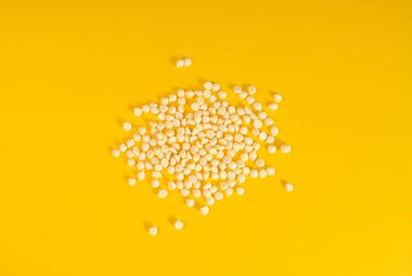 Beyaz çikolata parçacıkları, dağınık beyaz çikolata serpintileri, dekoratif kakao damlaları, Morsels, kurabiye dekorasyon malzemeleri, küçük şekerleme parçacıkları, sarı arka plan üst görünümü