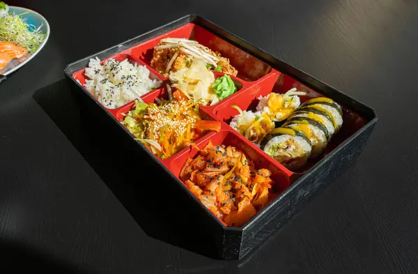 Japanese Lunch in Bento Box with Deep-Fried Squid Rings, Sushi Rolls, Salad, Rice, Pickled Ginger and Wasabi, Fish Maki Rolls, Japan Seafood, Asian Dinner in Japanese Restaurant