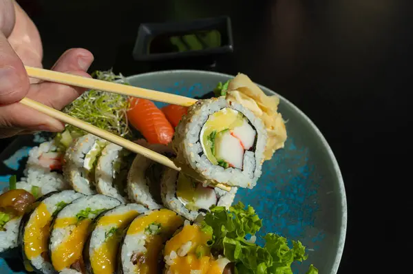 Eating Sushi Plate, Fish Maki Rolls in Hand, Japan Seafood, Sushi Set, Asian Dinner, Bamboo Sticks Tradition Nigiri Susi in Japanese Restaurant
