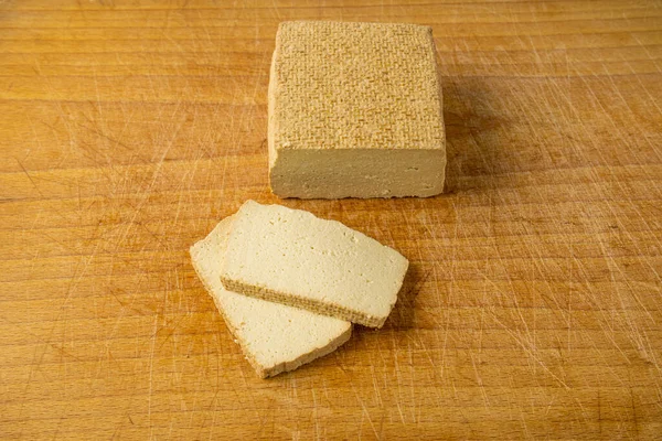 Tofu Cheese Block, Smoked Vegan Cheese Slice, Sliced Soya Bean Curd, Soy Protein or TSP Healthy Meat Analogue, Tofu Cheese on Wooden Cutting Board Background