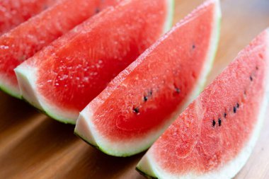 Karpuz dilimleri yakın plan. Su karpuzu yığını, Citrullus lanatus parçaları, kırmızı wassermelone kesme grubu, meyve parçası, ahşap zemin üzerinde karpuz