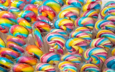 Renkli lolipop dokusu, çubukta sarmal şeker, renkli çizgili lolipop, yuvarlak meyve karamelli, çok renkli şekerleme, daire şeklinde lolipop yakın plan, seçici odak ve bulanık arkaplan