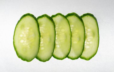 İzole edilmiş salatalık, yuvarlak salatalık dilimleri, salata için yeşil sebze dilimleri, sağlıklı doğal bitki parçaları, beyaz arka planda kesilmiş makro salatalıklar.