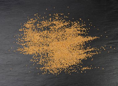 Hardal tohumları izole edilmiş, kuru sarı sinapis alba taneleri, siyah arka planda sivrisinek topları.