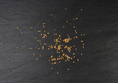 Hardal tohumları izole edilmiş, kuru sarı sinapis alba taneleri, siyah arka planda sivrisinek topları.