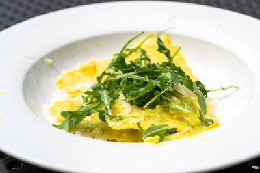Ravioli, peynirle doldurulmuş makarna, roka soslu, rendelenmiş peynir, limon aromalı krema sosunda servis edilen İtalyan mutfağı, öğle veya akşam yemeği için mükemmel, dokuma ve lezzeti ön plana çıkaran