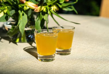 Tutku meyveli soğuk içecek, hoş geldin içkileri, sarı buzlu çay, küçük bardakta meyveli kokteyller güneşli bir yaz gününde bahçedeki restoran masasında buz.