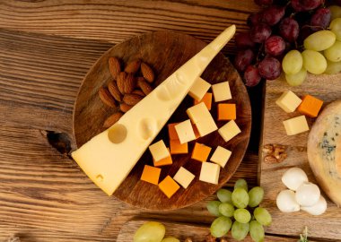 Cheese plate of color cheeses variety, yellow, white and blue gorgonzola platter, munster, fourme cheese board, assorted chopped dairy products, many stinky French cheeses on wood clipart