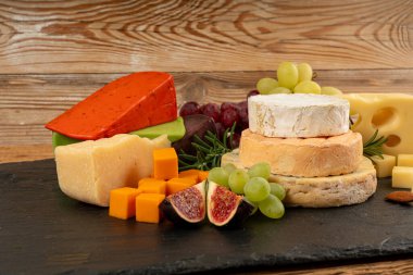 Peynir tabağı çeşitliliği, sarı, beyaz ve mavi gorgonzola tabağı, Munster, dört peynirli pano, çeşitli doğranmış süt ürünleri, ahşap üzerinde kokulu Fransız peyniri.