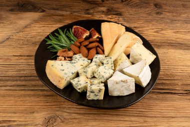 Peynir tabağı çeşitliliği, sarı, beyaz ve mavi gorgonzola tabağı, Munster, dört peynirli pano, çeşitli doğranmış süt ürünleri, ahşap üzerinde kokulu Fransız peyniri.