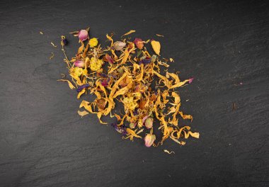 Kurutulmuş yenilebilir çiçek karışımı, Helichrysum arenaryum yığını, cüce yaprakları, siyah arka planda tıbbi bitki çayı yığını.