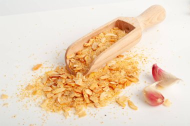 Kuru sarımsak dilimleri yalıtılmış, saçılmış, ahşap kepçesinde kızartılmış karanfil, ızgara sarımsak gevreği, beyaz arka planda karanfil grubu.