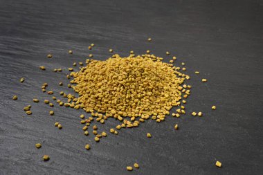 Fenugreek Seeds, Dry Trigonella, Spicy Methi Dana Grains, Indian Kitchen Seasoning Ingredient, Dry Yellow Fenugreek Seed Condiment on Black Stone Plate Background clipart