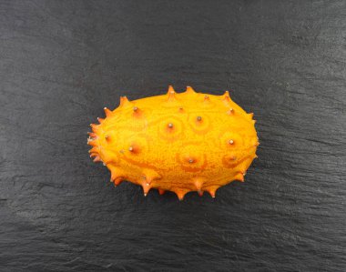 Kiwano on black plate, jelly melon, cucumis metuliferus ripe fruit, orange horned melon, african horned cucumber, spiked melon closeup clipart