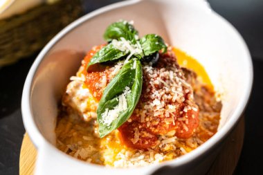 Lazanya porsiyonu, fırında lazanya, peynirli makarna, kıyma, domates. Güneşli bir yaz gününde, sokak restoranındaki masada lazanya, bulanık bir arka plan.