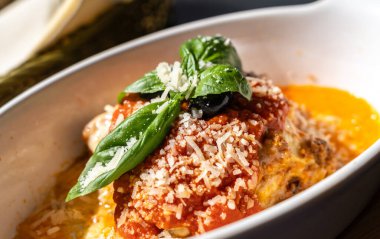 Lazanya porsiyonu, fırında lazanya, peynirli makarna, kıyma, domates. Güneşli bir yaz gününde, sokak restoranındaki masada lazanya, bulanık bir arka plan.