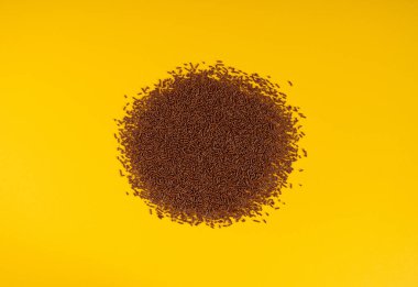 Çikolata serpintisi, çikolata serpintisi, şeker serpintisi, tatlı kahverengi gevrek süsleme, çikolata vermicelli, sarı arka plan üst görünümü