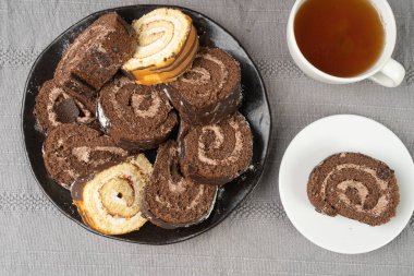 İsviçre çikolatalı dürüm, yuvarlak sünger keki, dilimlenmiş kakao kremalı vanilyalı bisküvi, İsviçre tatlısı, Rustik ahşap arka planda tombul kek.