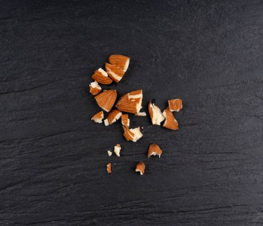 Ezilmiş bademler, fındık parçaları, dilimlenmiş badem tohumları ve siyah taş kaplama arka plan üzerindeki çekirdek koleksiyonu.