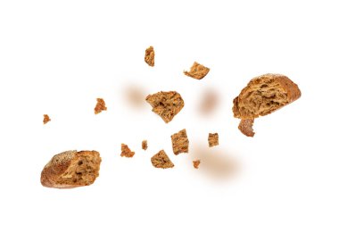 Kırık buğday ekmeği parçaları dökülüyor, tohumları uçuşan havuçlu havuç çörekleri, beyaz arka planda çavdar ekmekli tahıllı çörekler uçuyor.