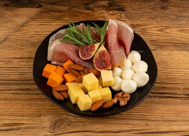 Prosciutto ile peynir tabağı, jambon, parma jambonu, kuru serrano dilimleri, iberico kapağı, peynir tabağı, çeşitli kesilmiş süt ürünleri, ahşap üzerinde kokulu Fransız peyniri.