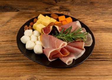 Prosciutto ile peynir tabağı, jambon, parma jambonu, kuru serrano dilimleri, iberico kapağı, peynir tabağı, çeşitli kesilmiş süt ürünleri, ahşap üzerinde kokulu Fransız peyniri.