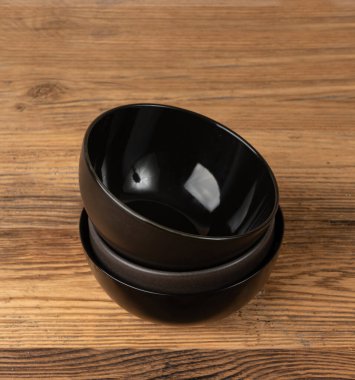 Masada boş kase yığını, ahşap masa üstünde siyah tabak, siyah porselen çanak modeli, metin için fotokopi alanı olan kırsal mutfak afişi.