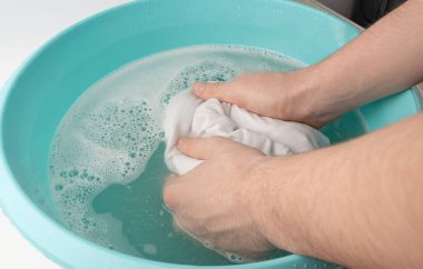 Çamaşırları mavi plastik bir leğenle yıkamak, ıslak beyaz bir bez, ev işi.