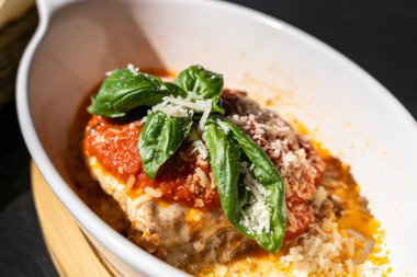 Lazanya porsiyonu, fırında lazanya, peynirli makarna, kıyma, domates. Güneşli bir yaz gününde, sokak restoranındaki masada lazanya, bulanık bir arka plan.