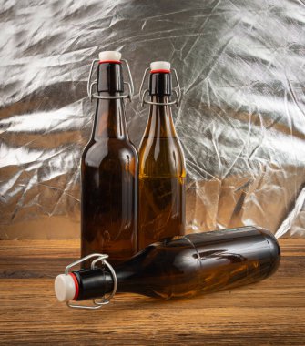 Eski bira şişesi, kahverengi cam şarap şişesi gümüş ve ahşap arka planda geleneksel kaliteli bir içki sembolü.